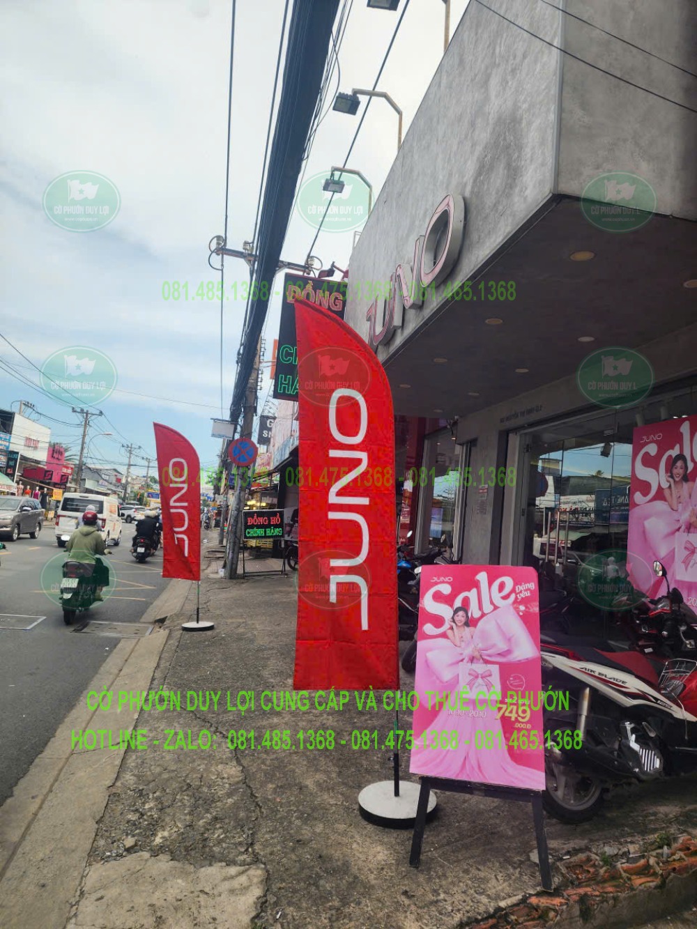 Cờ JUNO đặt cạnh bảng Sale trên vỉa hè trước cửa hàng