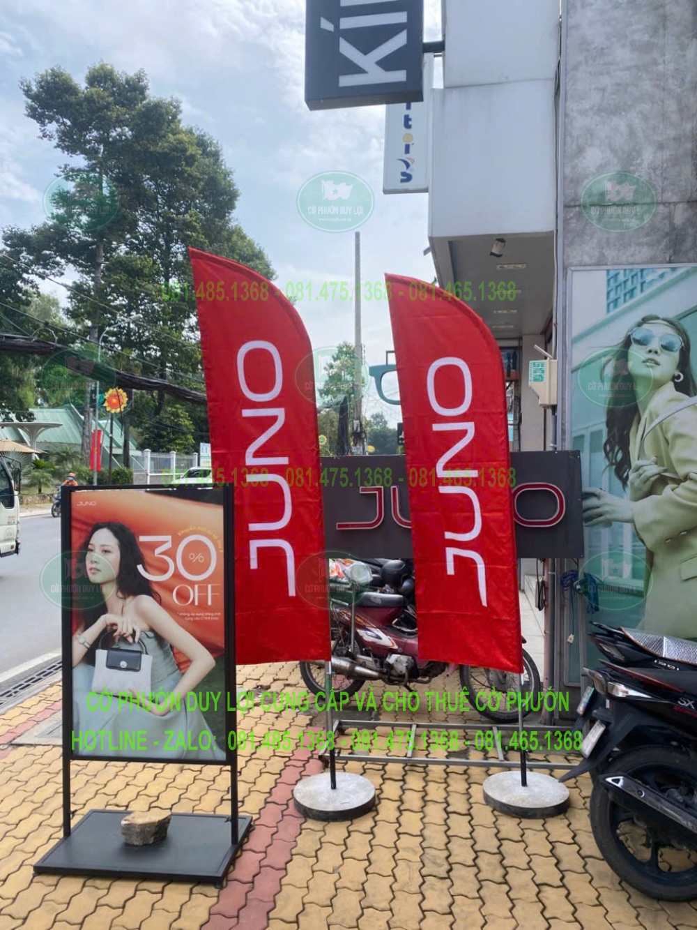 Hai bộ cờ JUNO màu đỏ đặt cạnh bảng quảng bá chương trình mua sắm