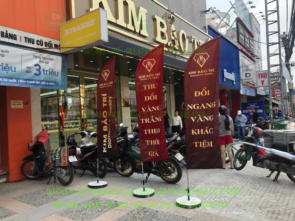 Ba mẫu cờ quảng cáo Kim Bảo Trí trước mặt tiền tiệm vàng